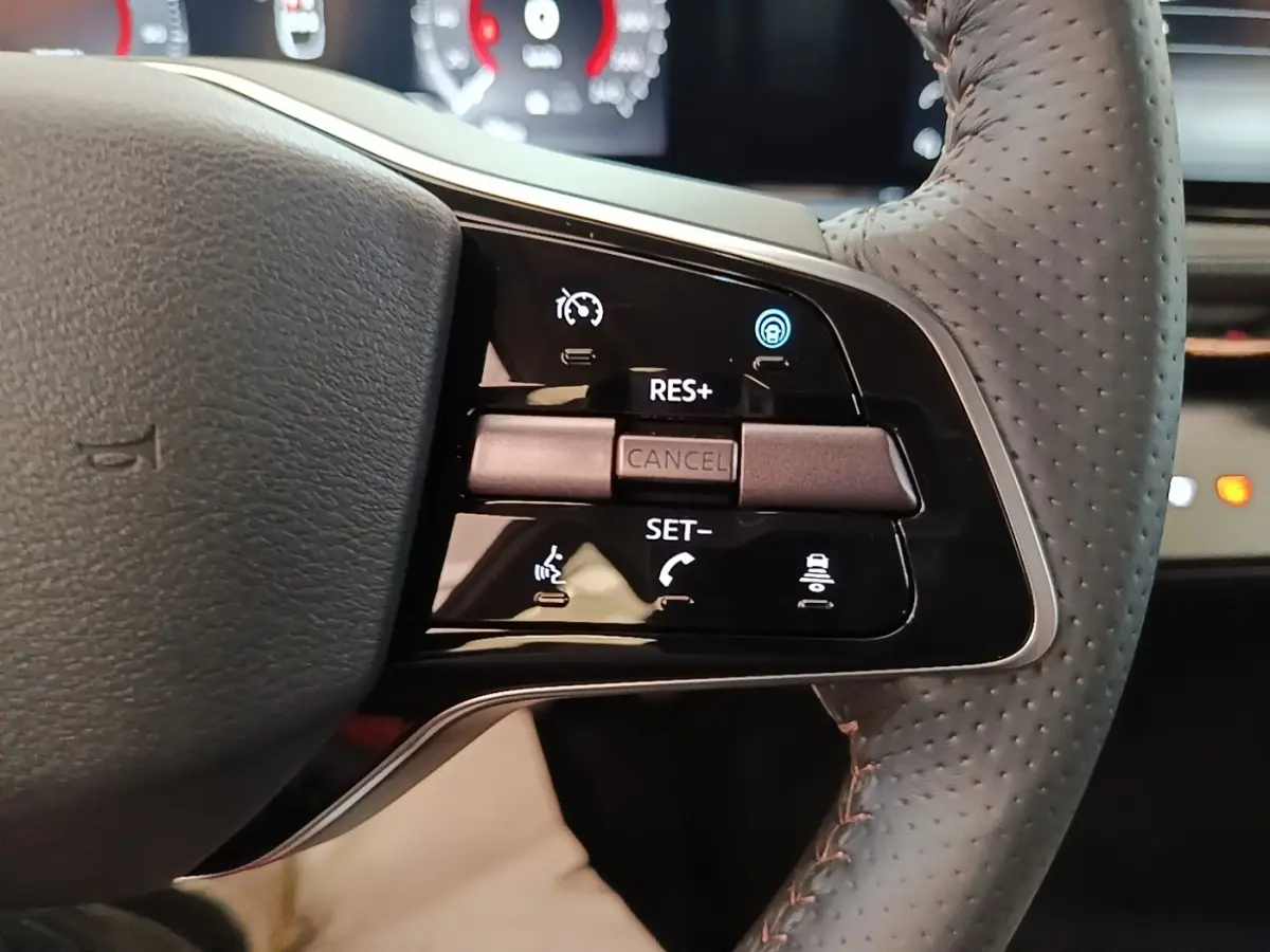 Gros plan sur la partie droite du volant cuir noir du Nissan Ariya 63kWh avec commandes multifonctions éclairées.