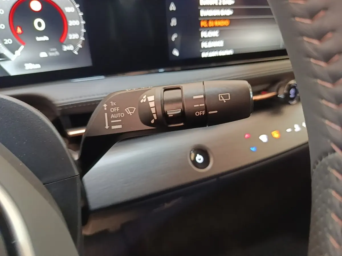 Gros plan sur la commande d’essuie-glace à gauche du volant cuir noir dans l’habitacle du Nissan Ariya 2026.