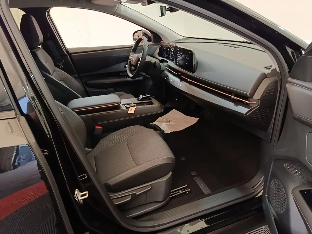 Intérieur avant droit du Nissan Ariya noir 2026, avec tableau de bord moderne et sièges tissu gris.