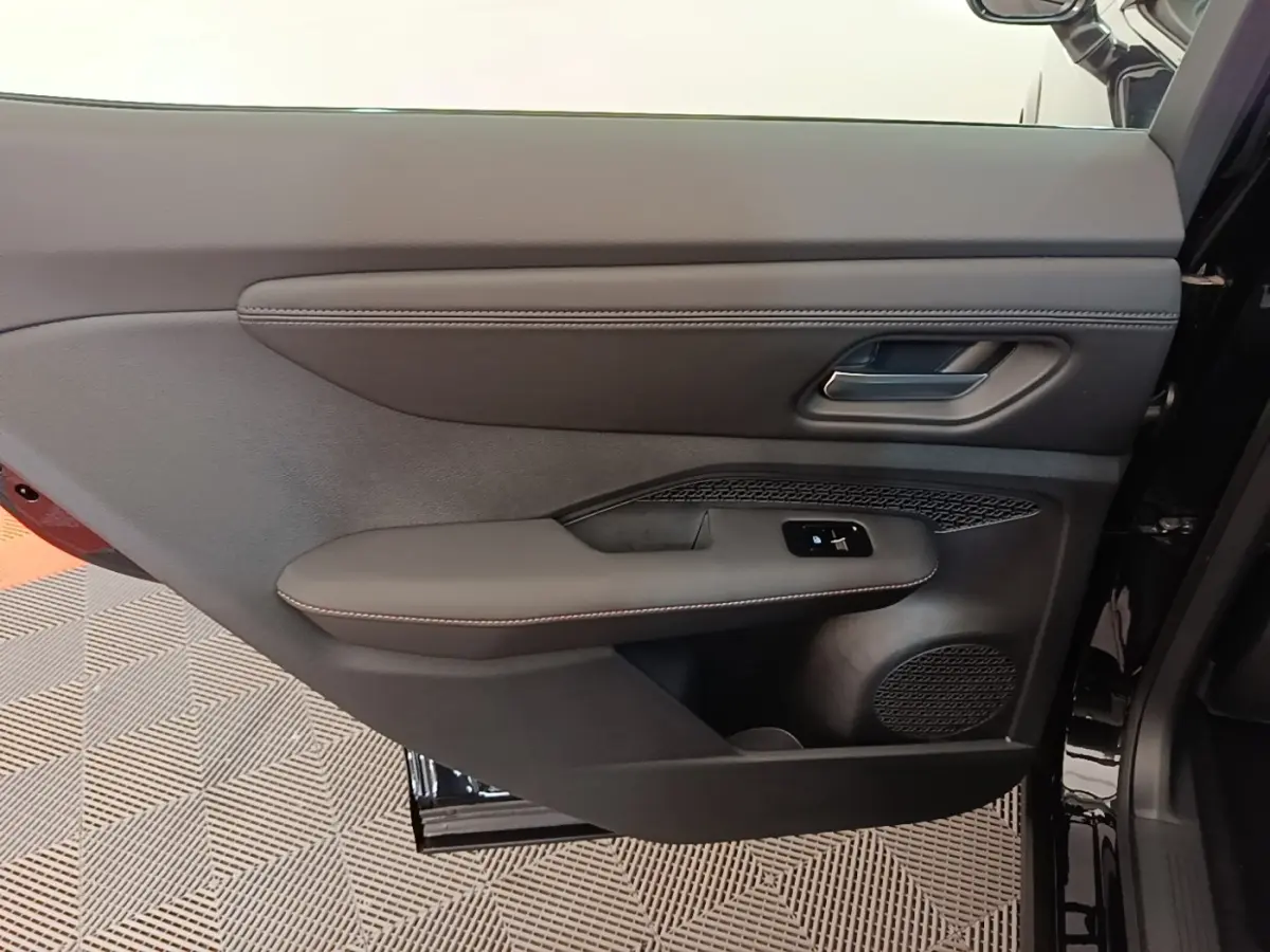 Gros plan sur la porte avant droite noire du Nissan Ariya 63kWh 218ch Engage avec commandes de vitre et haut-parleur intégré.
