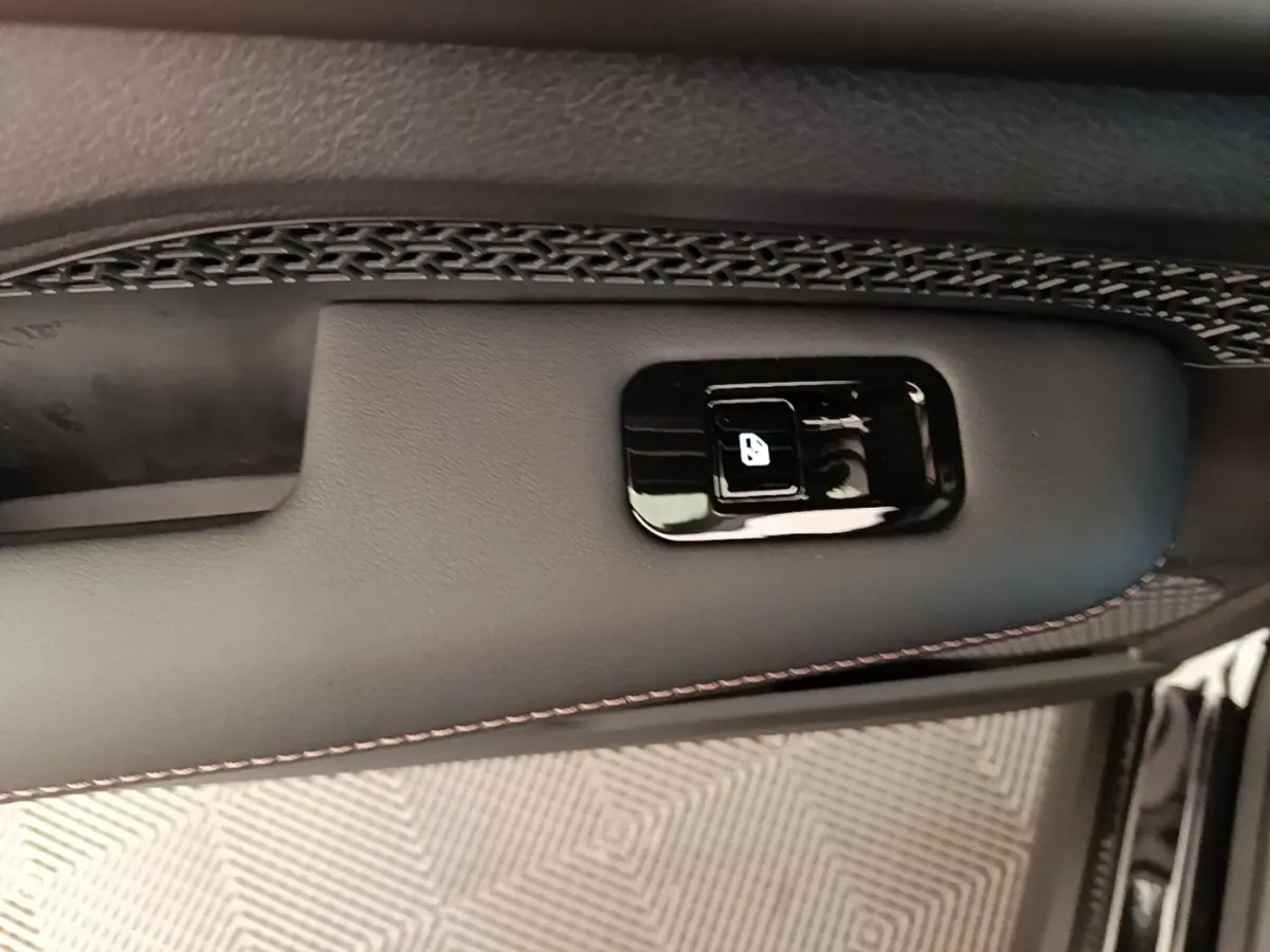 Gros plan sur la commande de verrouillage de porte noire intégrée à la garniture intérieure noire avec surpiqûres rouges du Nissan Ariya.