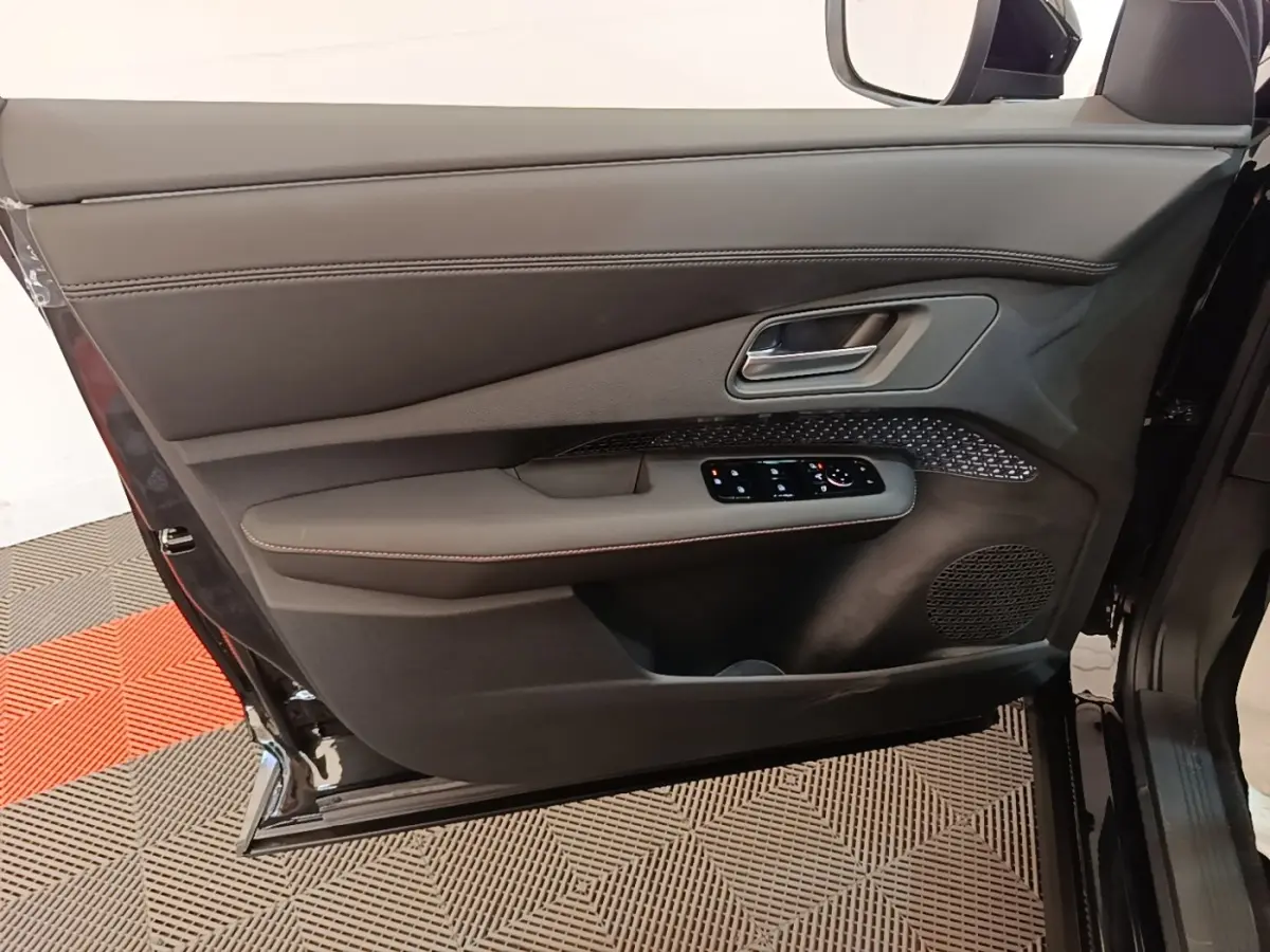 Porte avant gauche ouverte du Nissan Ariya noir, montrant les commandes électriques et le revêtement intérieur en cuir.