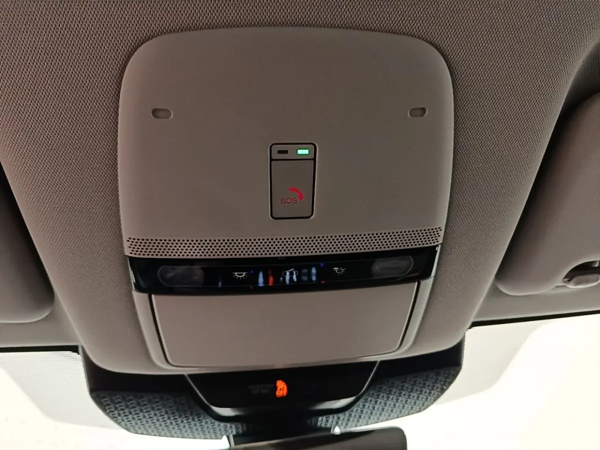 Vue intérieure du plafonnier beige du Nissan Ariya noir 2026 avec bouton SOS et éclairages intégrés.