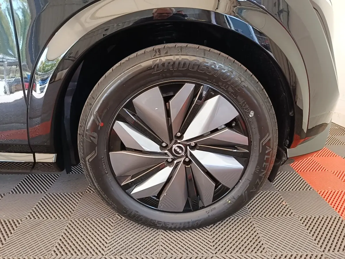 Gros plan sur la roue avant droite noire du Nissan Ariya 63kWh 218ch Engage avec jante design bicolore.