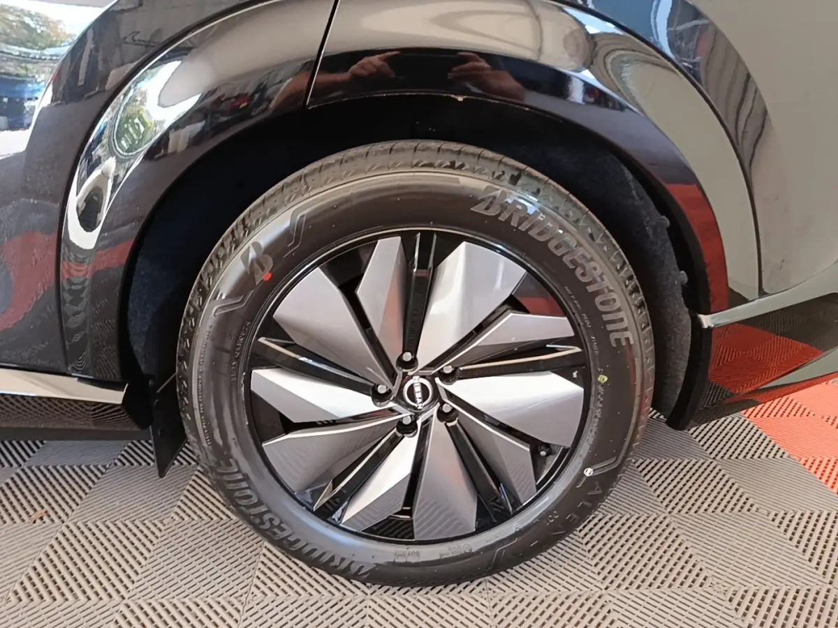 Gros plan sur la roue arrière droite noire du Nissan Ariya 63kWh 218ch Engage avec jante design bicolore.