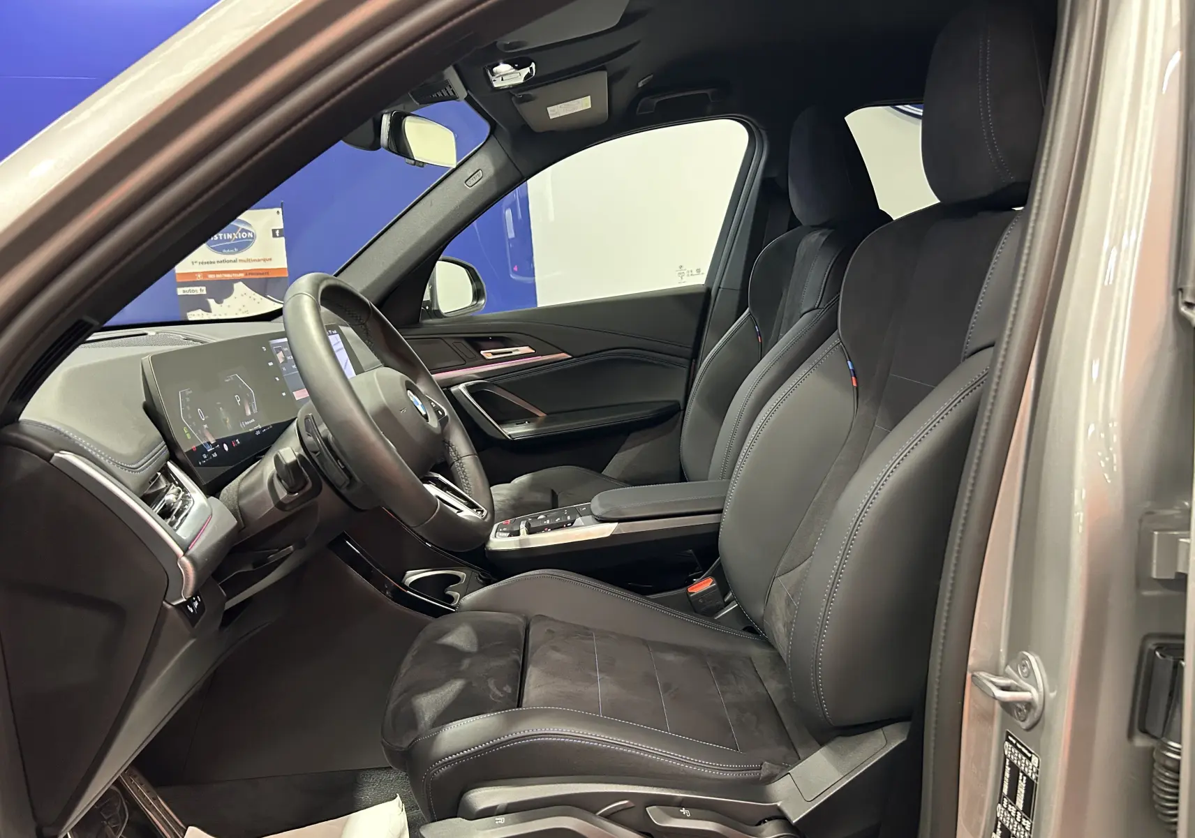 Intérieur avant droit du BMW X1 Spacesilber 2024 avec sièges sport M en cuir et tableau de bord digital.