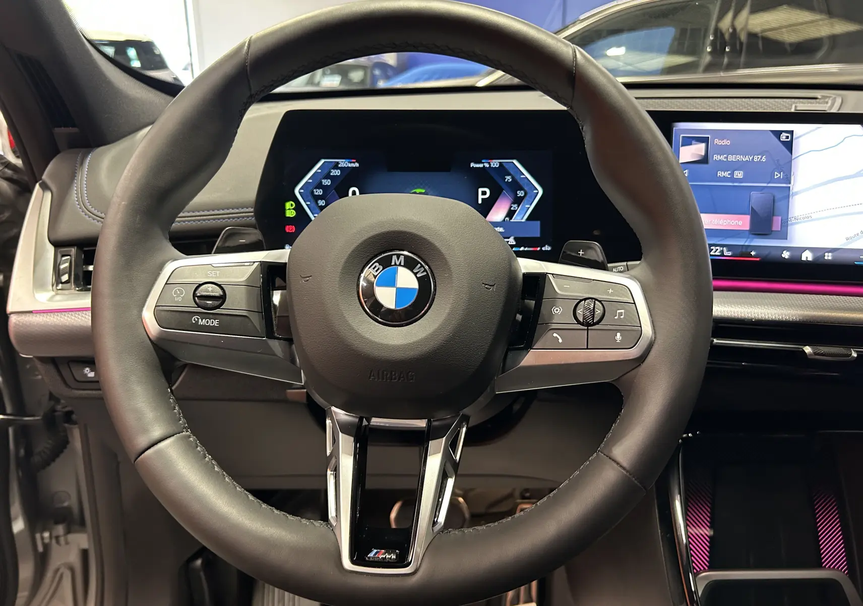 Volant cuir M Sport de BMW X1 2024 avec commandes intégrées et tableau de bord numérique lumineux.