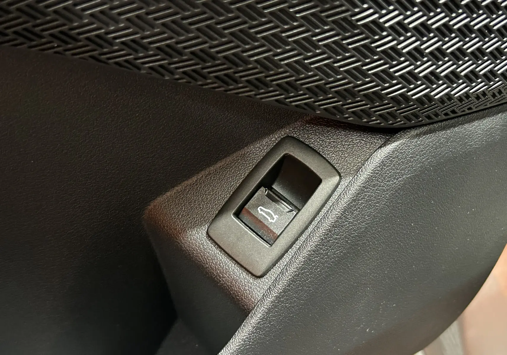 Gros plan sur le bouton d'ouverture du hayon dans l'habitacle du BMW X1 Spacesilber 2024.