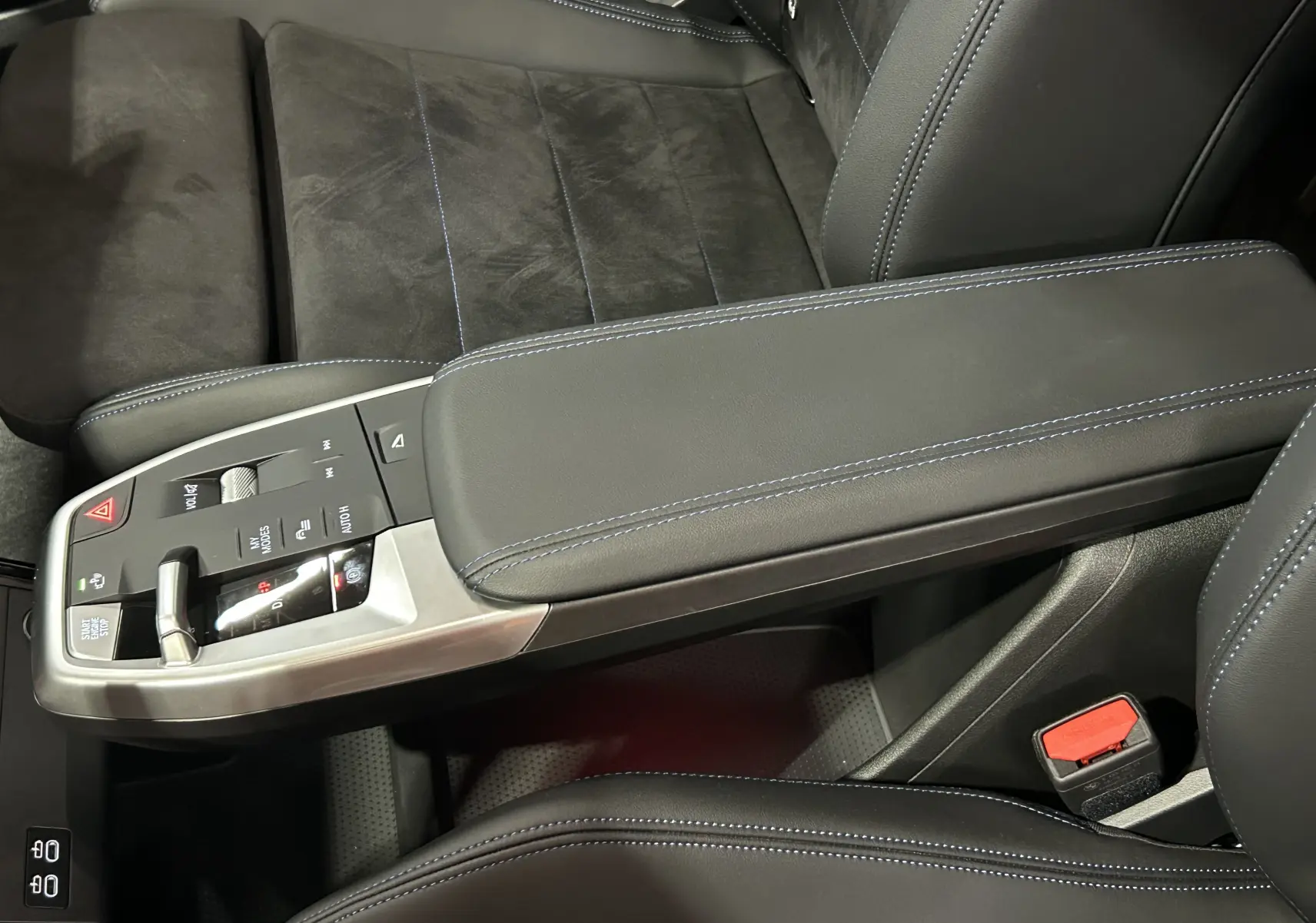 Gros plan sur la console centrale et siège avant en cuir noir avec surpiqûres bleues du BMW X1 2024 Spacesilber.