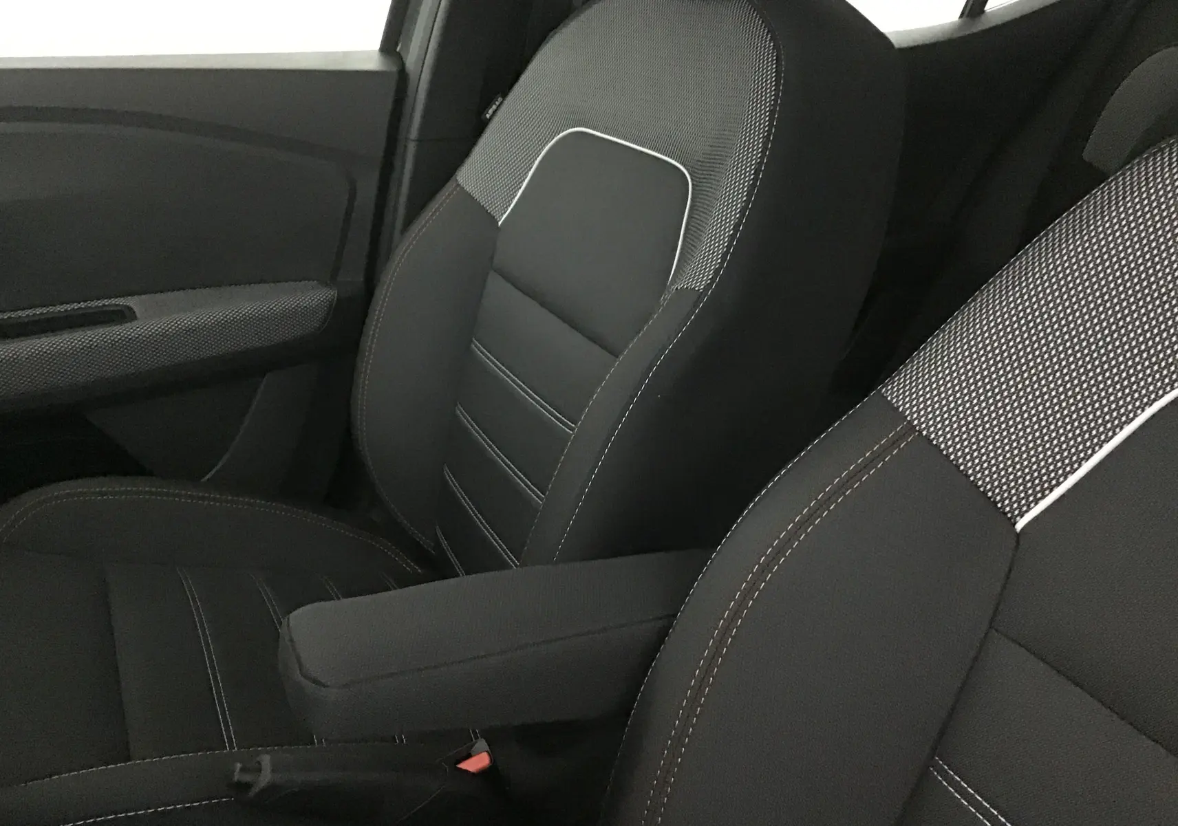 Gros plan sur les sièges avant noirs avec surpiqûres blanches et tissu texturé de la Dacia Sandero Stepway 2025.