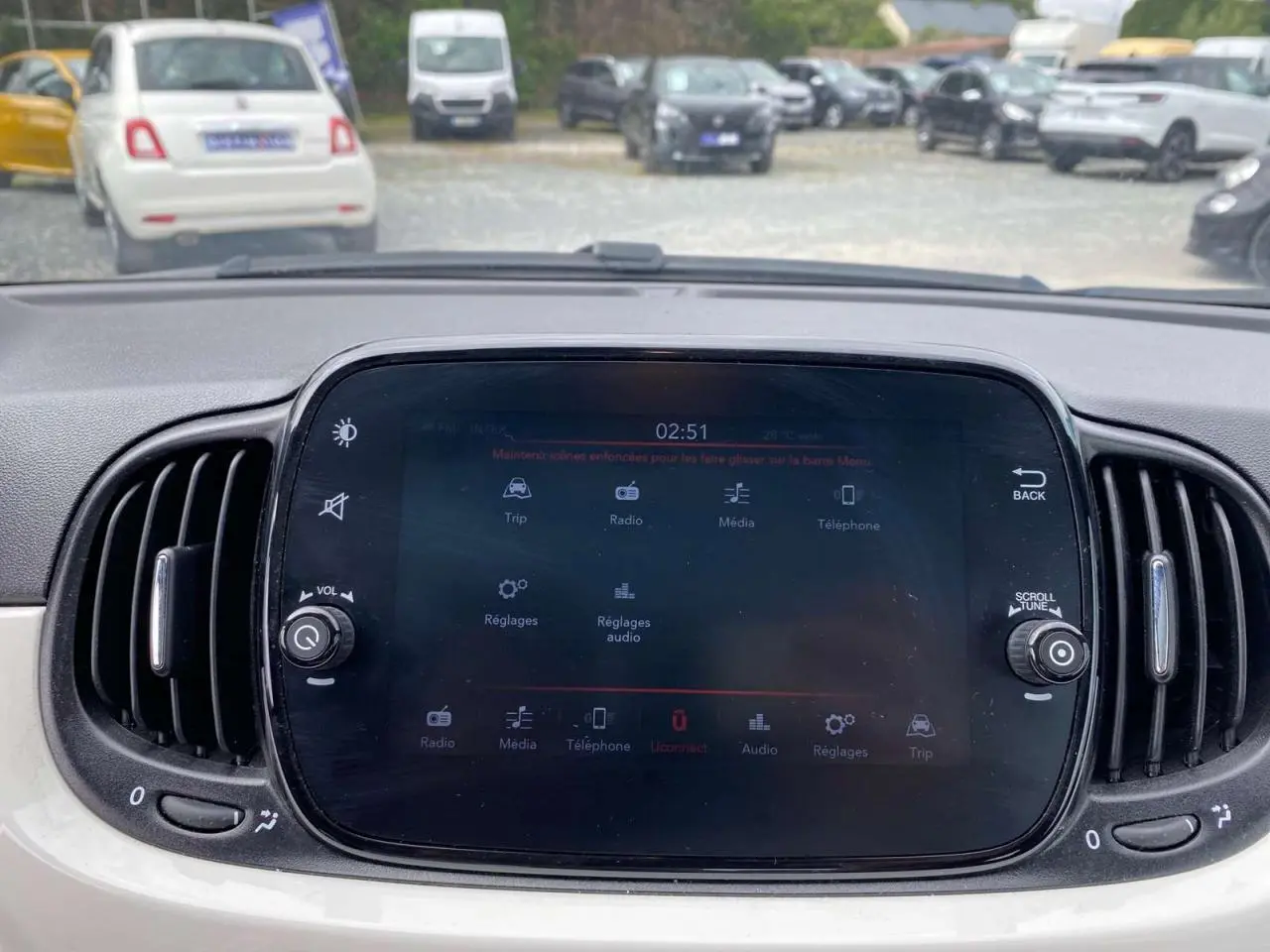 Écran tactile central du tableau de bord du Fiat 500 blanc, avec commandes multimédia et aérateurs latéraux visibles.