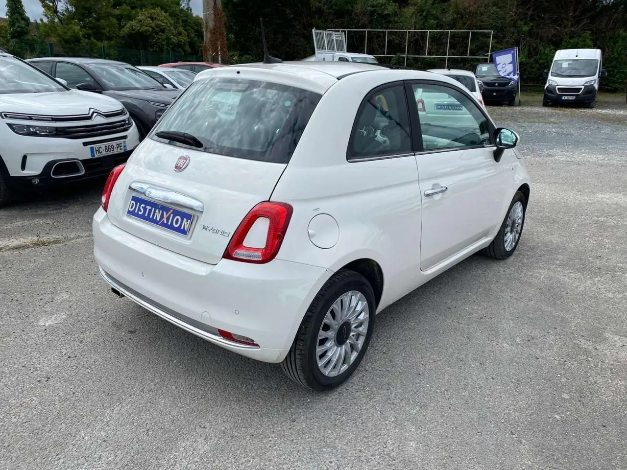 Vue 3/4 arrière droite d'une FIAT 500 blanche 2024 avec jantes alliage 16'' Spider et toit panoramique fixe.