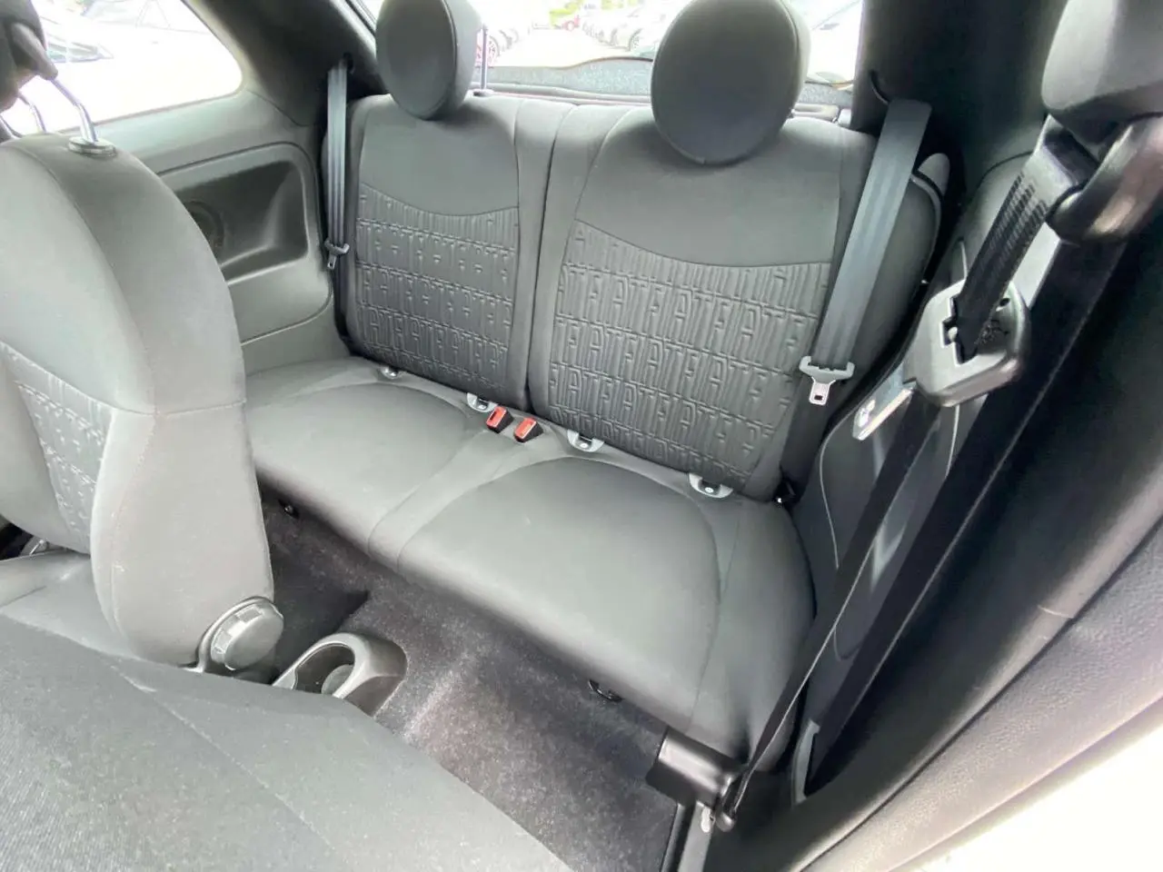Vue intérieure de la banquette arrière noire de la Fiat 500 2024 avec appuie-têtes ronds et ceintures visibles.