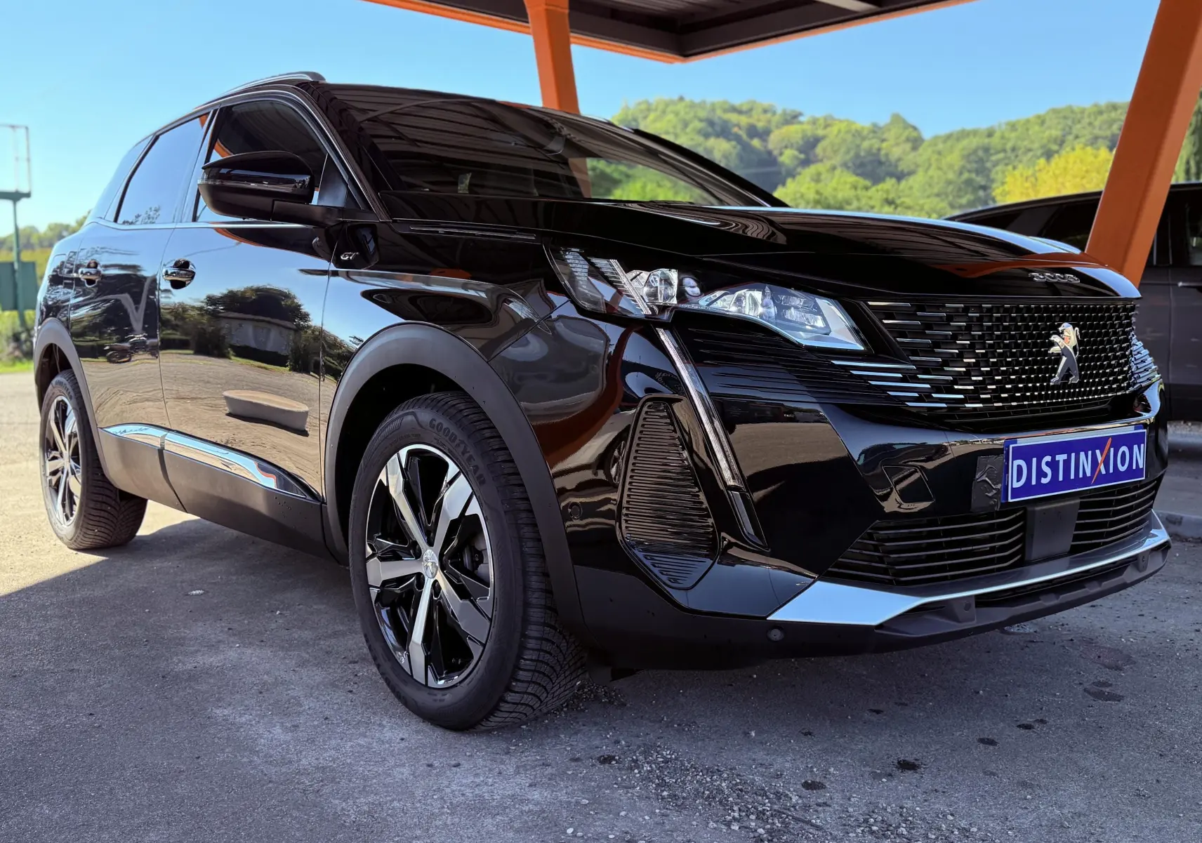 Peugeot 3008 noir perle métal vu en 3/4 avant droit sous abri avec jantes noires et logo GT sur aile.