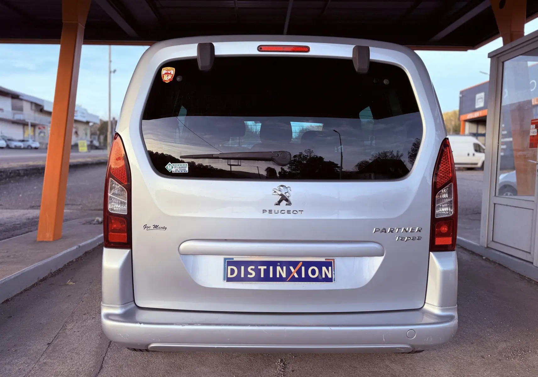 Vue arrière d'un Peugeot Partner Tepee gris 2014 avec logo et plaques distinctives sous un abri.