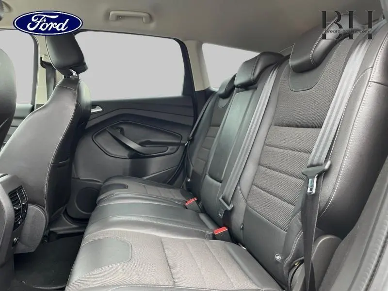 Vue latérale intérieure des sièges arrière en cuir noir du Ford Kuga gris Magnetic, avec ceintures de sécurité visibles.