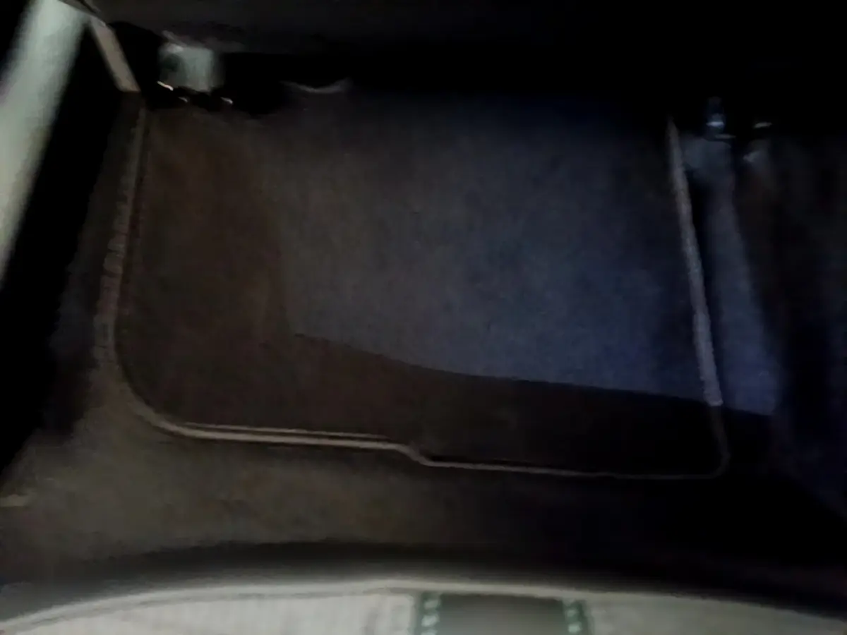 Tapis de sol noir en tissu dans l'habitacle avant d'un Peugeot 2008 gris clair, vue plongeante intérieure.