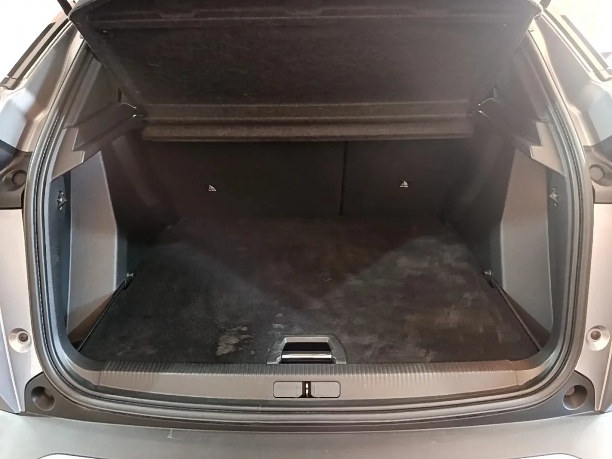 Coffre ouvert vu de l'arrière d'un Peugeot 2008 gris clair, montrant l'espace de chargement vide et la tablette de séparation.