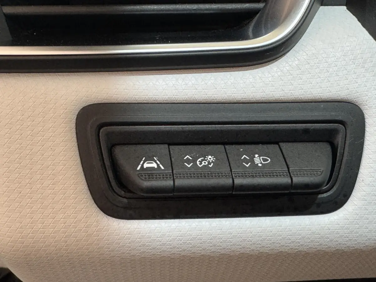 Gros plan sur les commandes d'assistance à la conduite sur panneau blanc texturé intérieur Renault Clio Business TCe 100 GPL 2023.