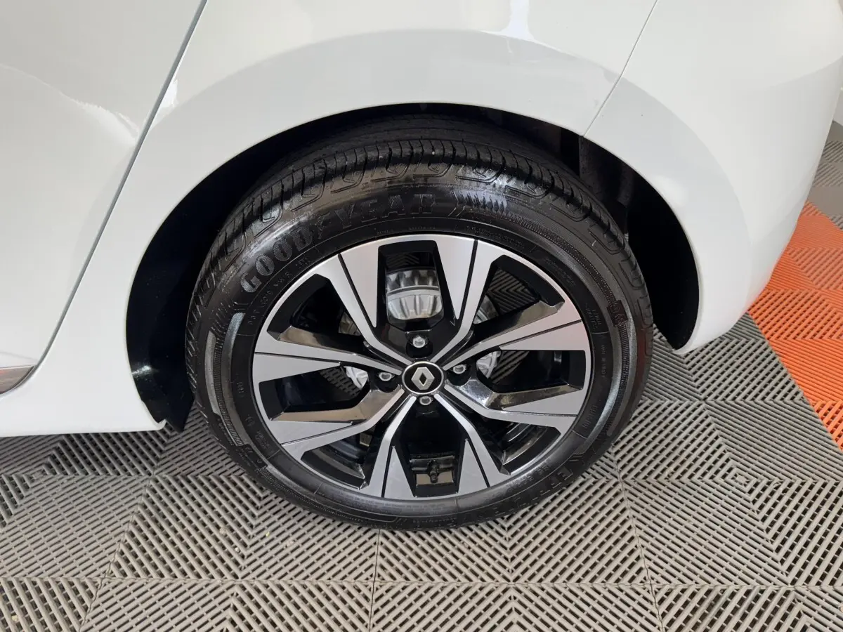 Gros plan sur la roue arrière droite d'une Renault Clio blanche 2023 avec jante alliage noire et argentée.