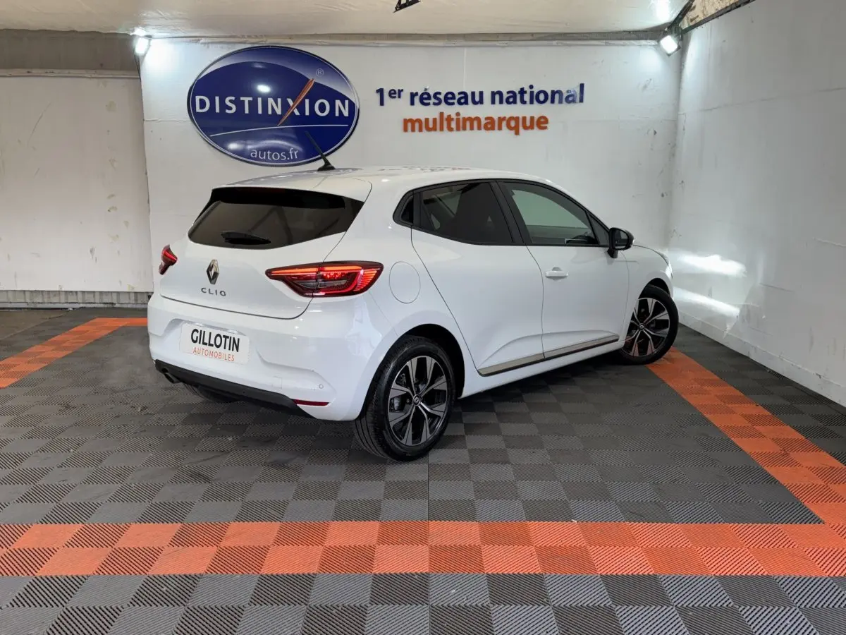 Renault Clio Business blanc vue 3/4 arrière droit, avec jantes alliage et feux arrière LED allumés.