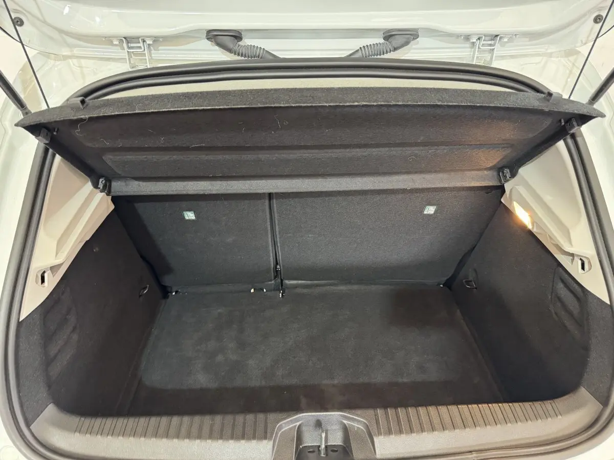 Coffre ouvert vu de l'arrière d'une Renault Clio Business blanc, espace de chargement propre et vide avec éclairage intérieur.