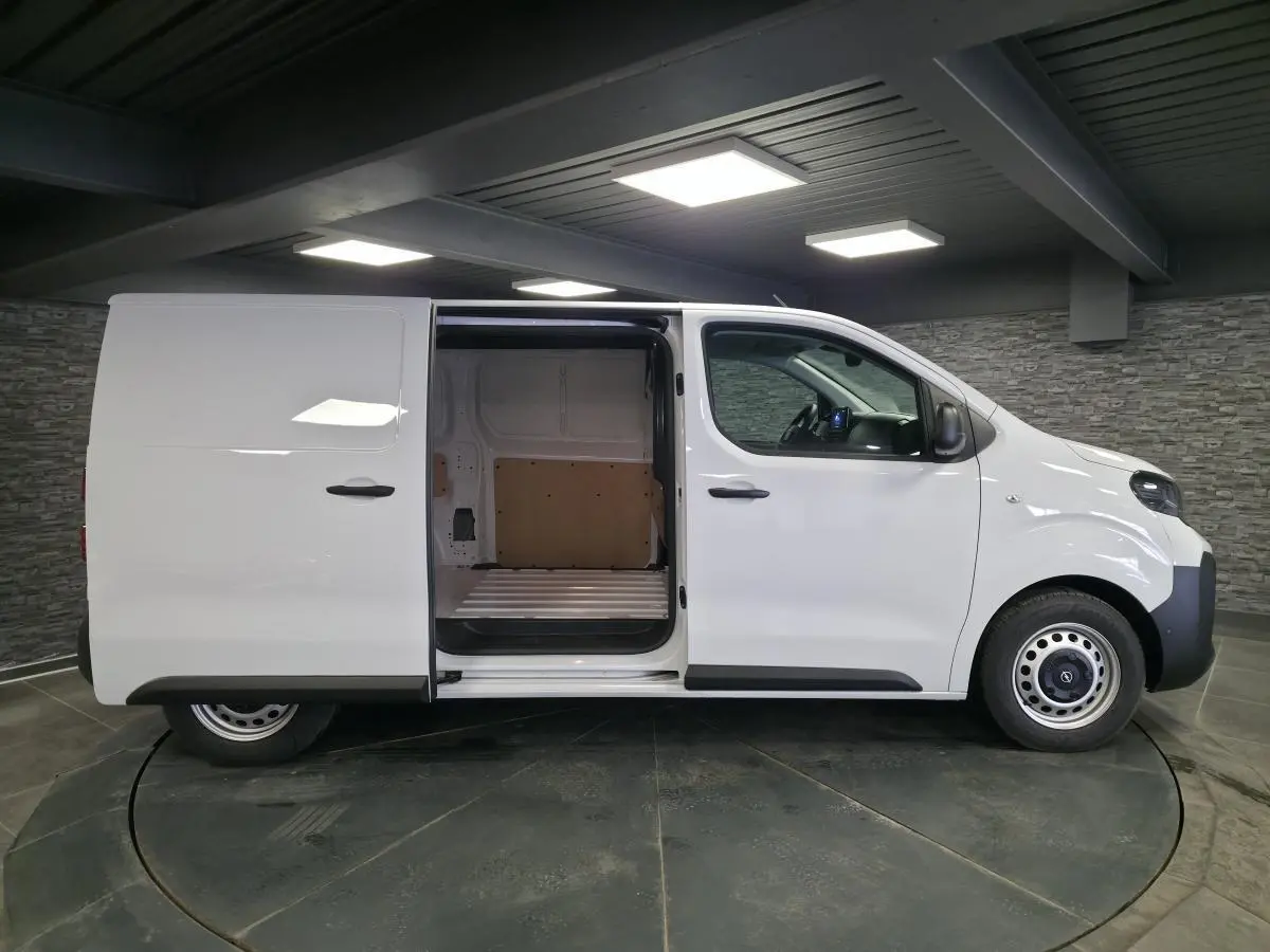 Profil droit d’un utilitaire Opel Vivaro blanc 2025 avec porte latérale coulissante ouverte montrant l’espace de chargement.