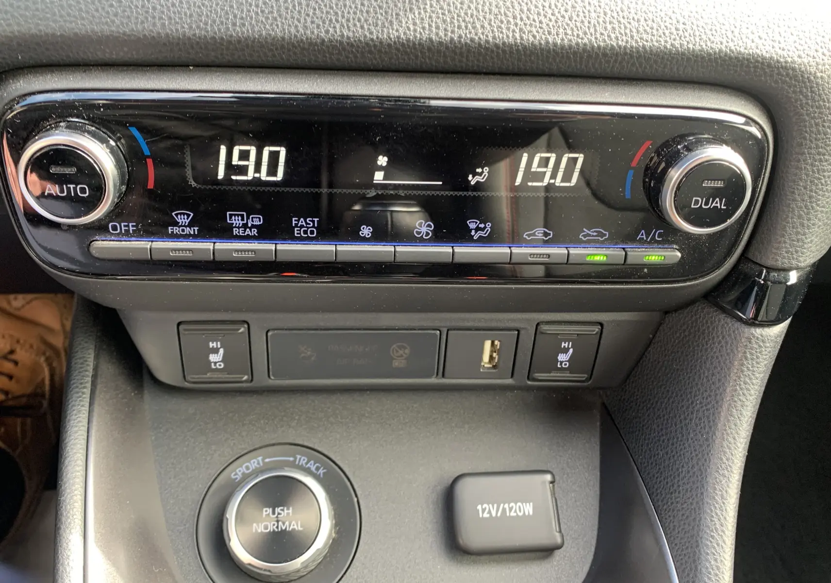 Gros plan sur la console centrale de la Toyota Yaris 2021, montrant la climatisation digitale et les commandes de modes de conduite.