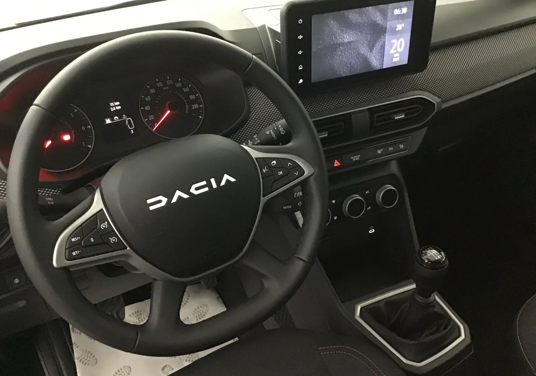 Vue intérieure du tableau de bord et volant DACIA Sandero Stepway 2025 avec écran tactile et levier de vitesse manuel.