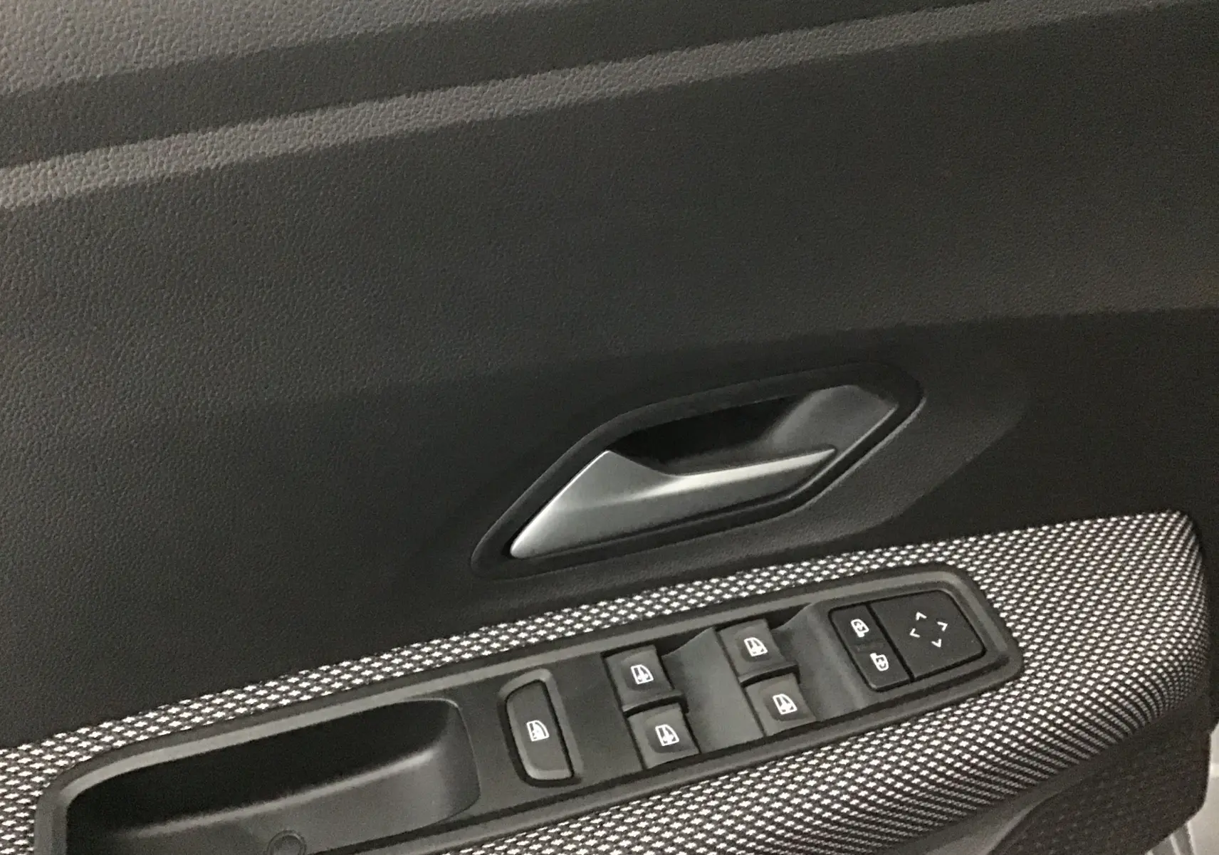 Gros plan sur la commande des vitres électriques côté gauche de la porte d'une Dacia Sandero Stepway gris schiste.