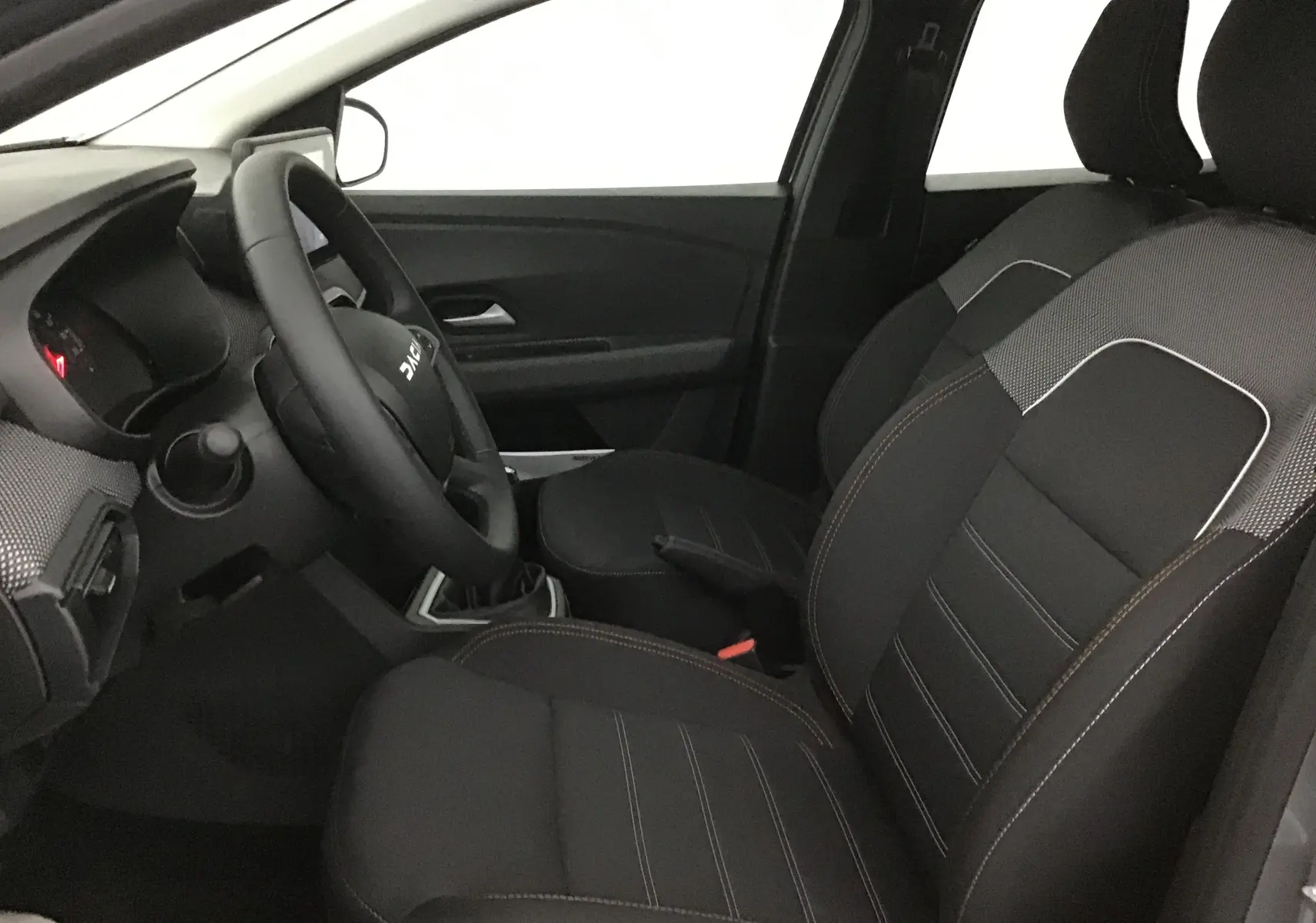 Intérieur de la Dacia Sandero Stepway 2025 vu côté gauche, sièges chauffants avec sellerie spécifique Stepway noire et grise.