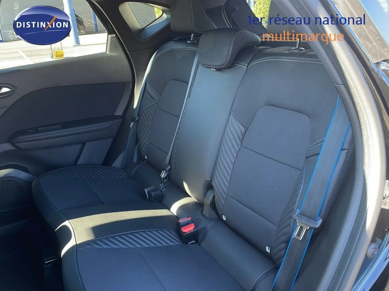 Vue intérieure côté droit des sièges arrière noirs du Renault Captur E-Tech hybride 2025 avec surpiqûres bleues et ceintures assorties.