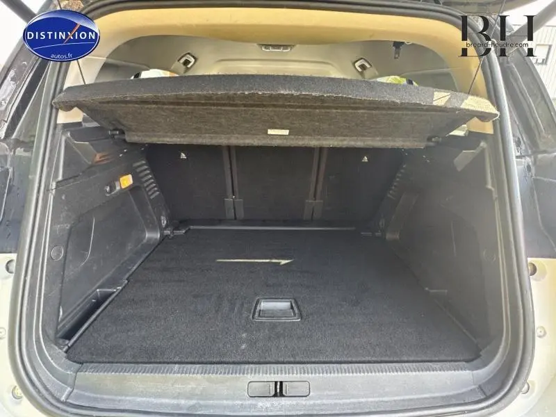 Coffre ouvert vu de l'arrière d'un Citroën C5 Aircross blanc nacré avec cache-bagages relevé et espace de chargement vide.