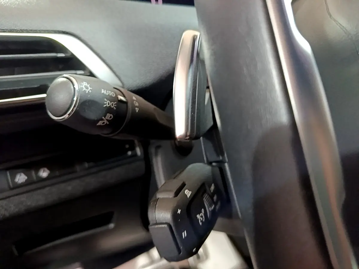 Gros plan sur la commande des phares et régulateur de vitesse au volant cuir du Peugeot 3008 PureTech 130 GT.