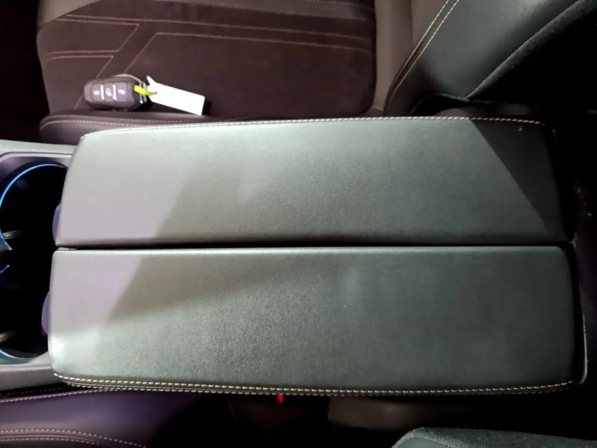 Vue plongeante sur l'accoudoir central en cuir noir avec surpiqûres contrastantes du Peugeot 3008 bleu PureTech 2021.