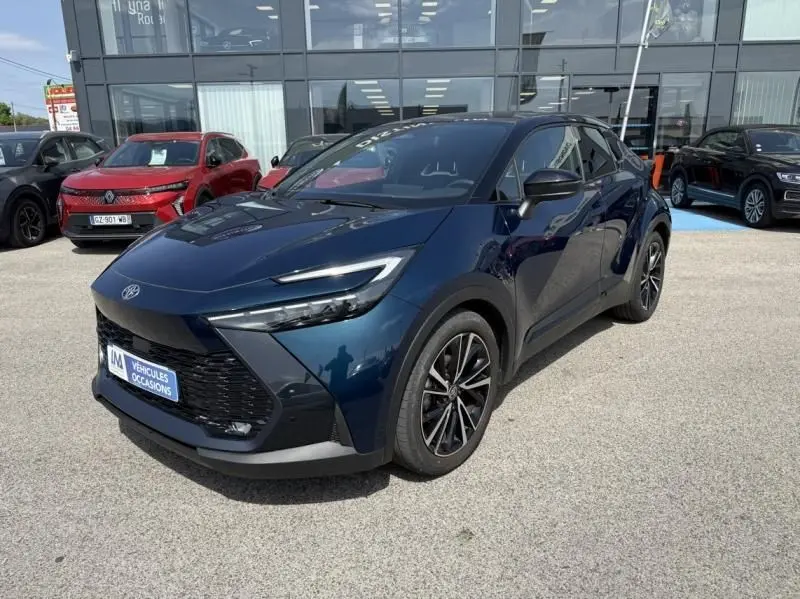 Toyota C-HR Hybride 2024 bleu persan en 3/4 avant droit, avec calandre large et jantes alliage noires distinctives.