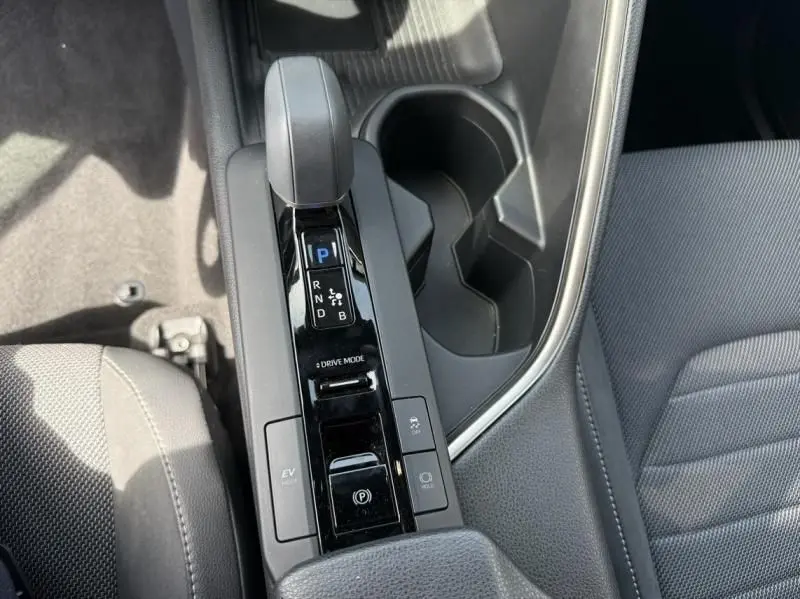 Vue rapprochée de la console centrale noire avec levier de vitesse automatique et porte-gobelets du Toyota C-HR Hybride 2024.