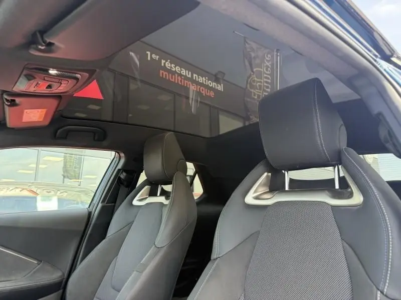 Vue intérieure du Toyota C-HR Hybride 2024 montrant les sièges avant en tissu gris et noir avec appuie-têtes ajourés.