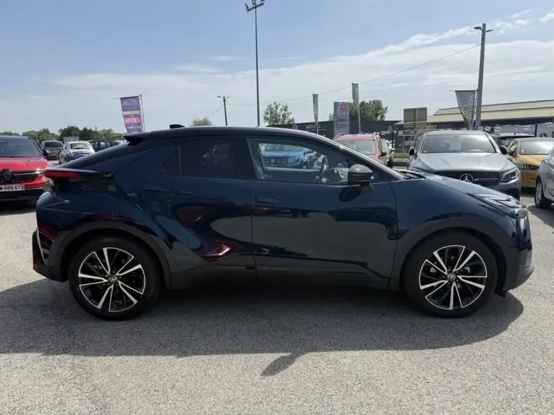 Vue de profil côté gauche du Toyota C-HR Hybride 2024 bleu persan avec jantes alliage noires et détails sportifs.