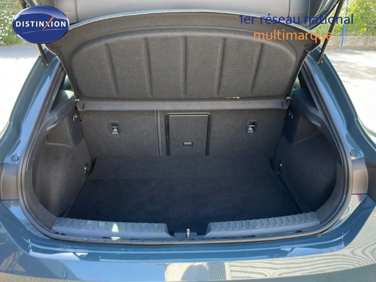 Coffre ouvert vu de l'arrière d'une CUPRA Leon 1.5 eTSI 150CH DSG bleu Fjord, intérieur du coffre en tissu noir.