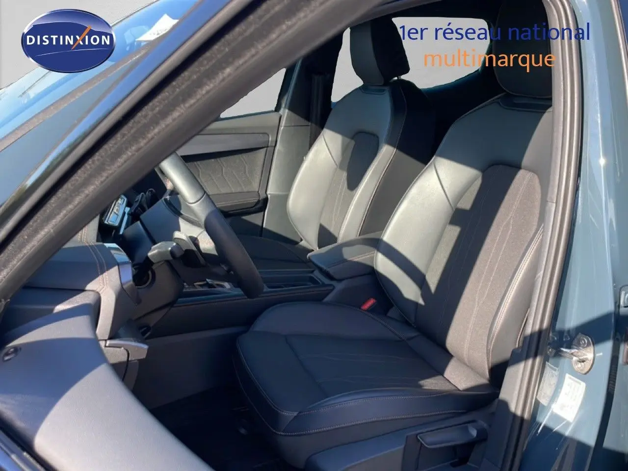 Vue intérieure côté conducteur de la CUPRA Leon 1.5 eTSI 150CH en bleu Fjord, sièges en cuir noir avec surpiqûres contrastées.