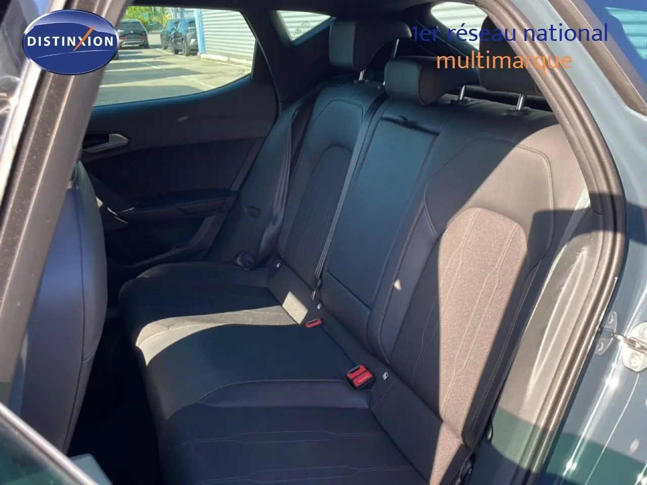 Vue intérieure sur les sièges arrière en tissu noir de la CUPRA Leon 1.5 eTSI 150CH DSG, porte arrière ouverte côté droit.