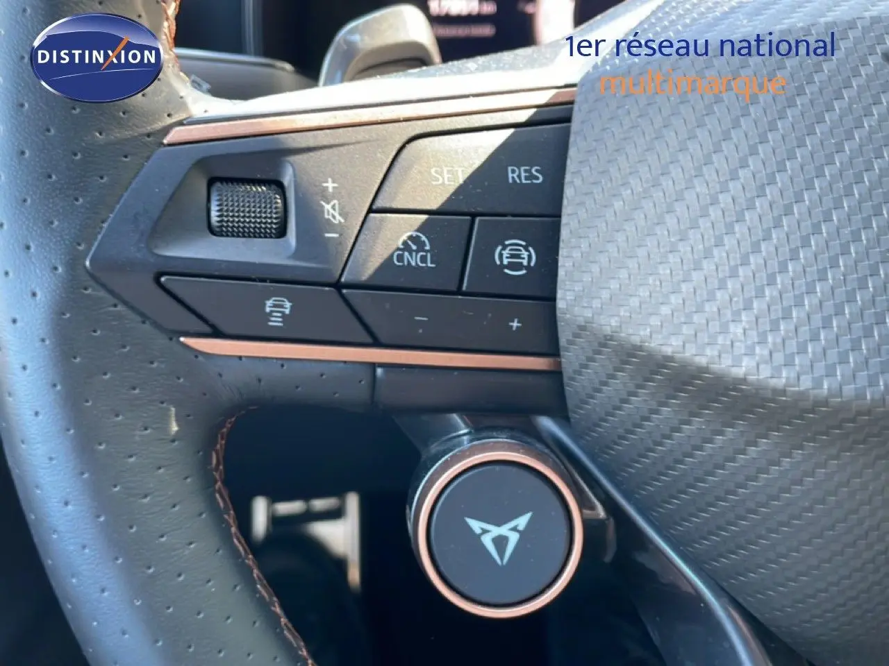 Gros plan sur le volant en cuir perforé avec commandes intégrées et logo CUPRA, intérieur noir du Leon 1.5 eTSI bleu Fjord.