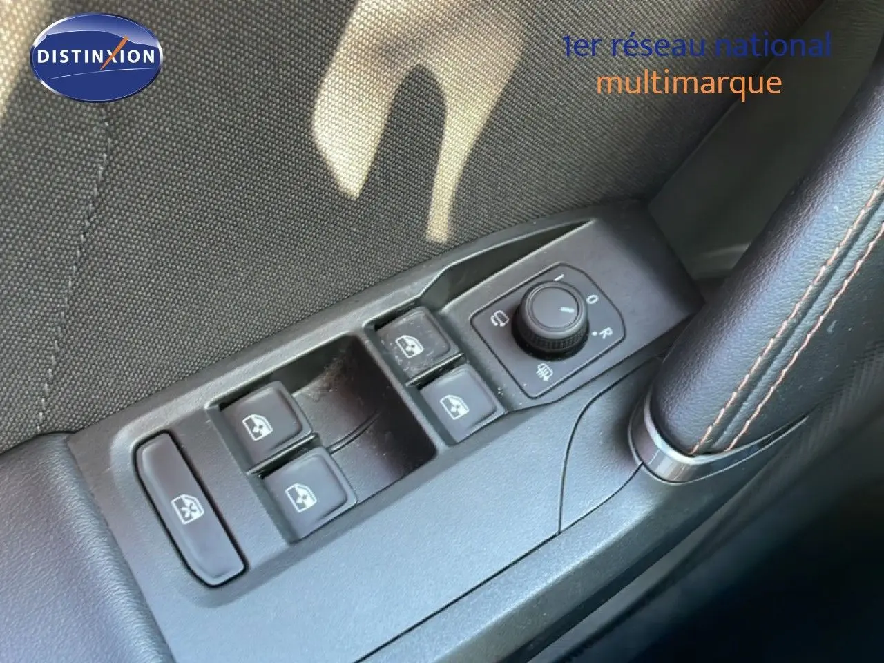 Gros plan sur les commandes de lève-vitres et réglage des rétroviseurs côté conducteur d’une CUPRA Leon bleu Fjord.