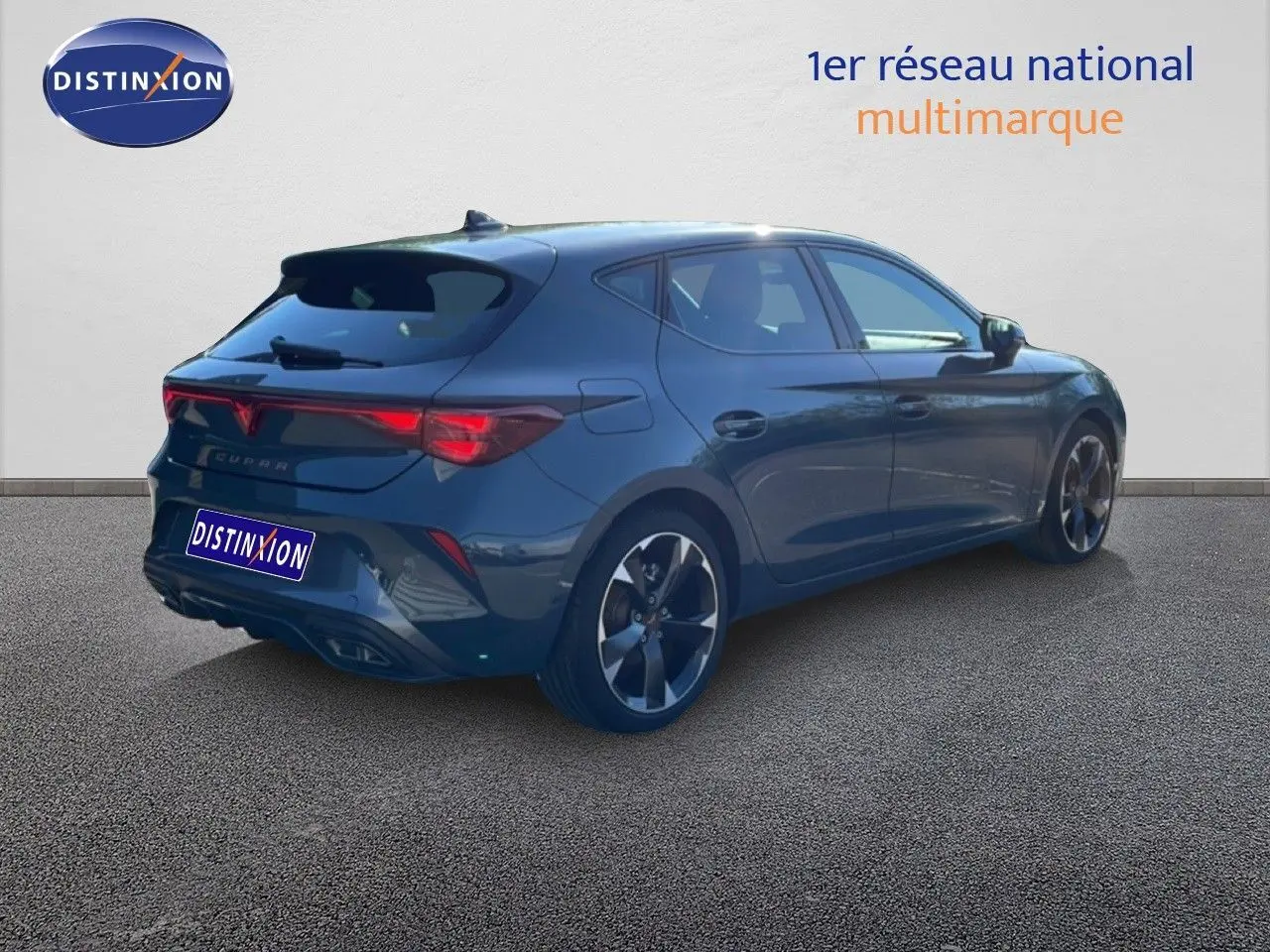 Vue 3/4 arrière droite d'une CUPRA Leon 1.5 eTSI 150CH DSG bleu fjord avec jantes bi-ton et feux LED distinctifs.