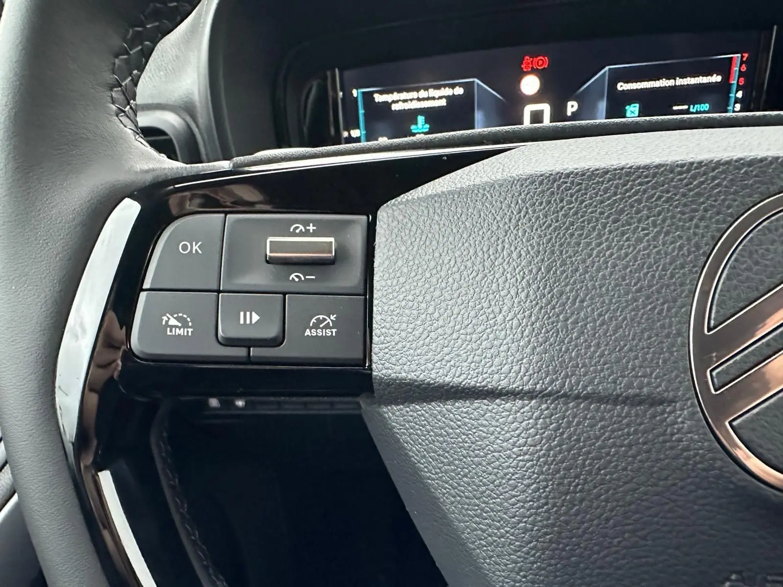 Gros plan sur la partie gauche du volant gris du Citroën Berlingo 2025 avec commandes de régulateur et tableau de bord numérique.