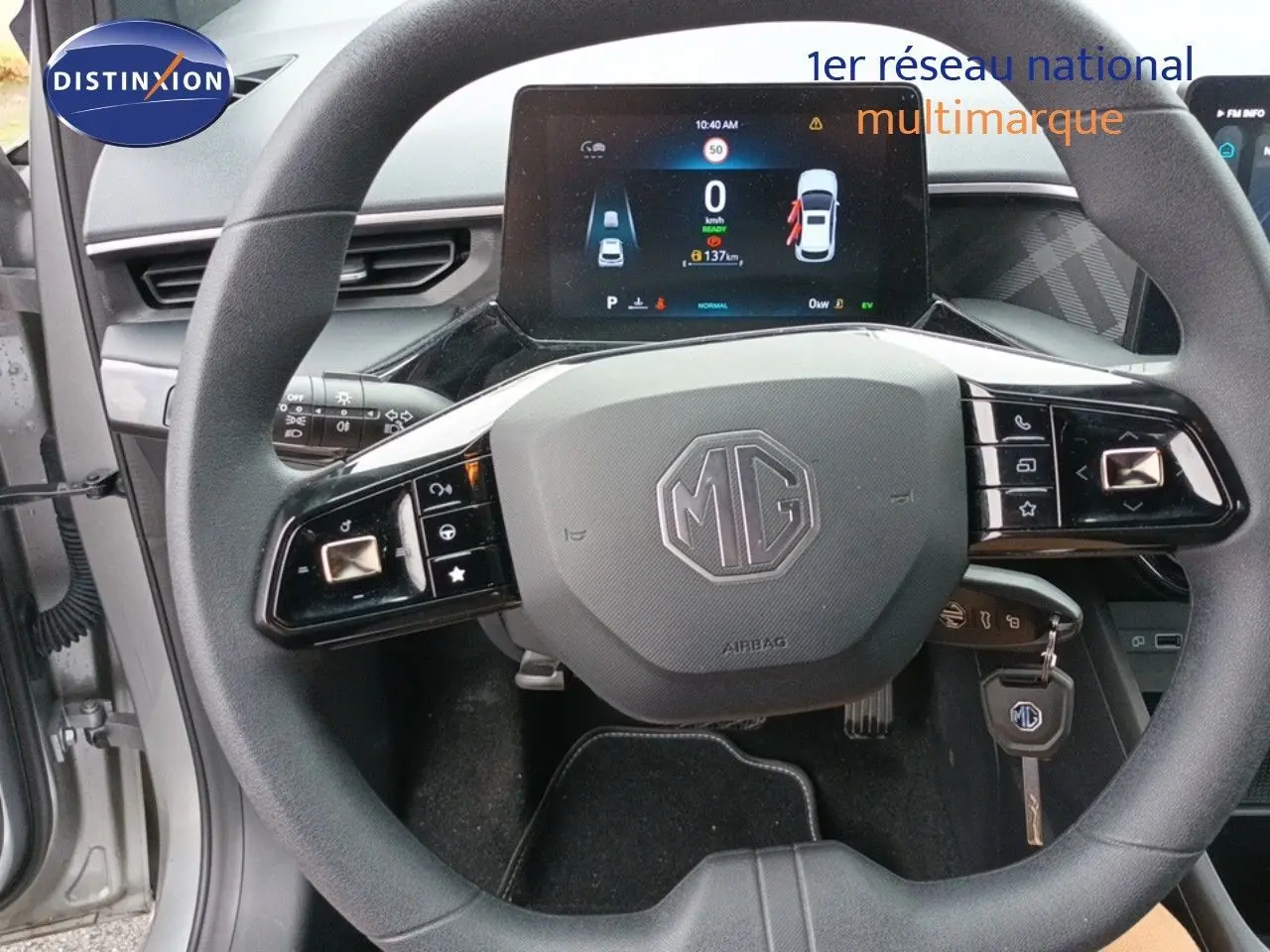 Vue rapprochée du volant MG d’une MG3 gris 2024 avec tableau de bord numérique et clé insérée.