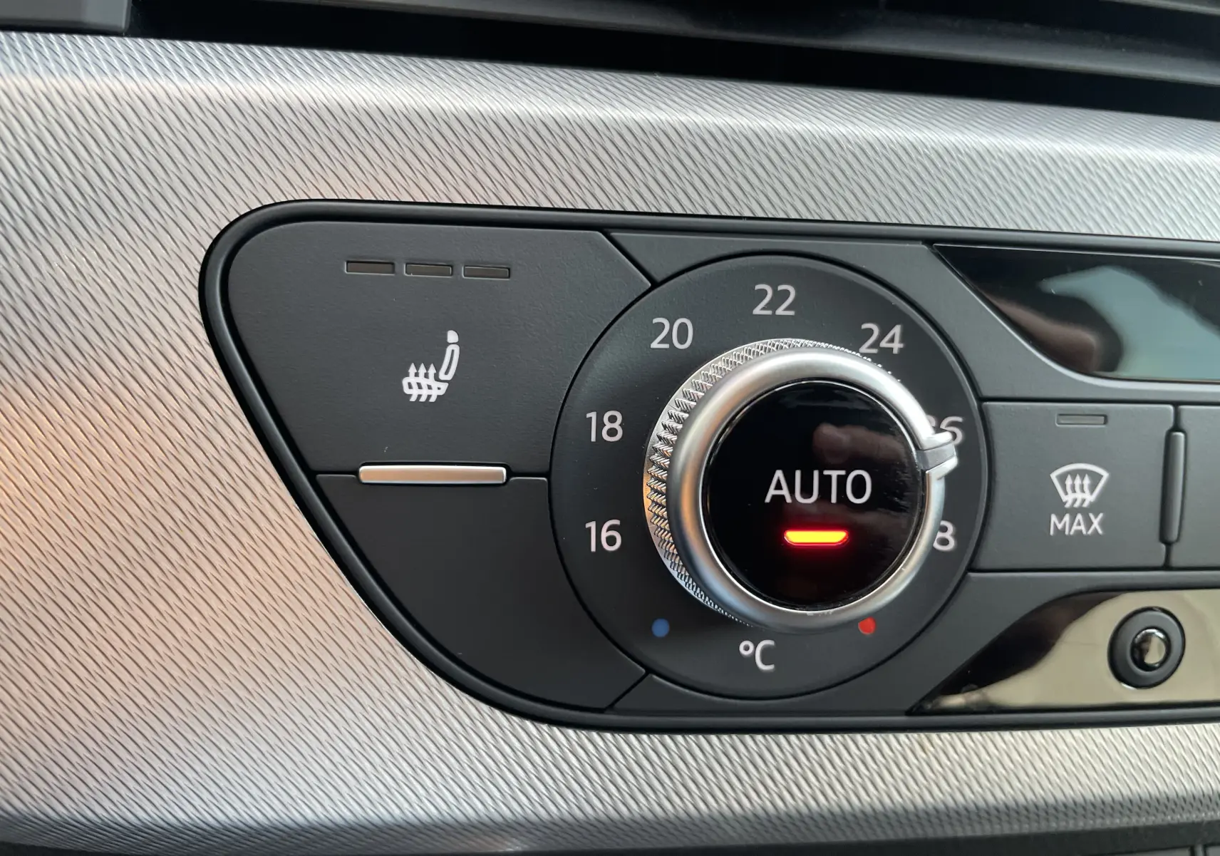 Gros plan sur le bouton de réglage automatique de la climatisation avec fonction siège chauffant de l’Audi A4 Avant blanc 2022.