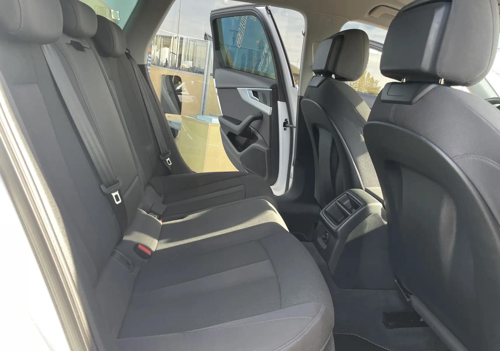 Vue intérieure arrière droite de l'Audi A4 Avant 40 TDI blanc, sièges tissu gris foncé et porte arrière ouverte.