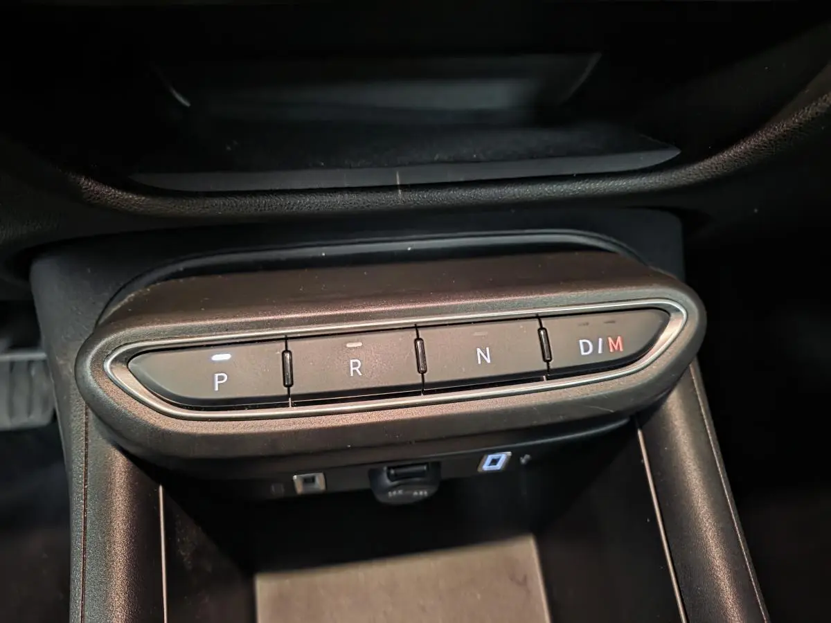 Gros plan sur les boutons de la boîte automatique de la FIAT 600 rouge, affichant les modes P, R, N et D/M.